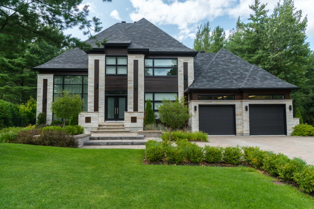 Elegant Two-Story Home with Modern Stone and Wood Facade Elegant two-story home featuring a modern facade with a mix of stone and wood accents, large windows, a double garage, and well-manicured landscaping in the front yard.